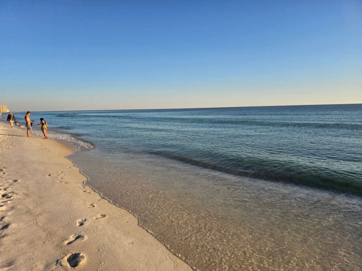 footsteps in white sand beach along the waters edge