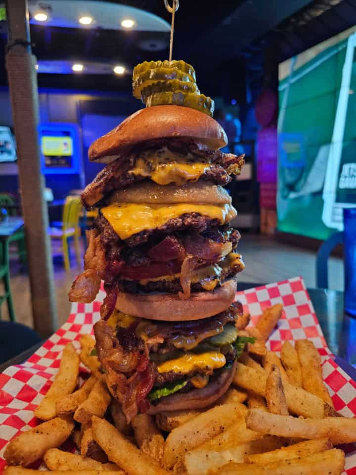 Big Kahuna Burger layered with 8 burger patties, bacon cheese, onions, and more over a basket of fries