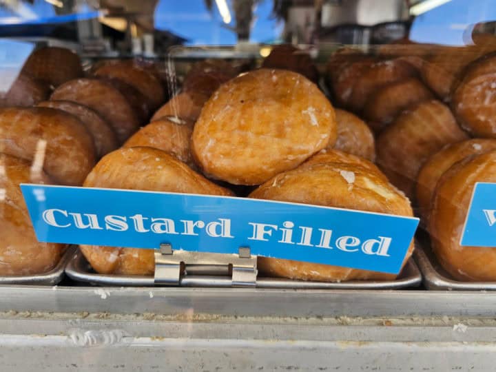 Custard filled donuts on a silver tray in a display case