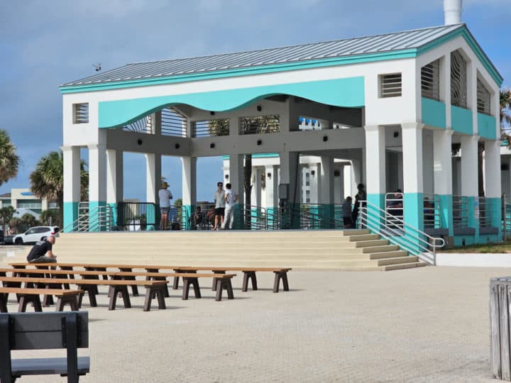 turquoise and white covered pavillion near rows of benches