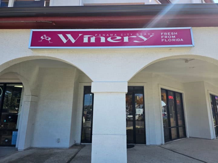 Pink Panama City Beach Winery sign over two arches and the entrance to the store