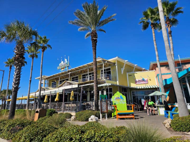 Margaritavilla Restaurant exterior with palm trees, and large neon green Adirondack chair