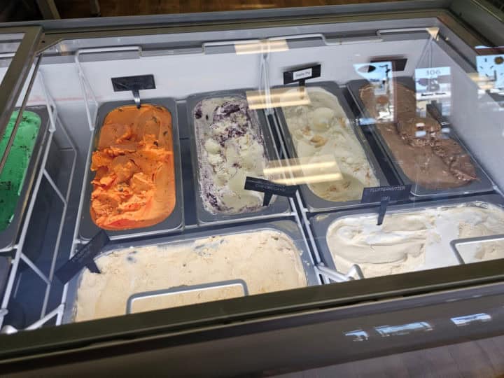 ice cream in metal tubs in a cooler case