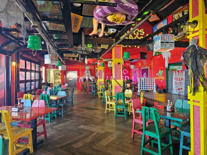 indoor seatig with multiple color tables and chairs, art all over the ceiling