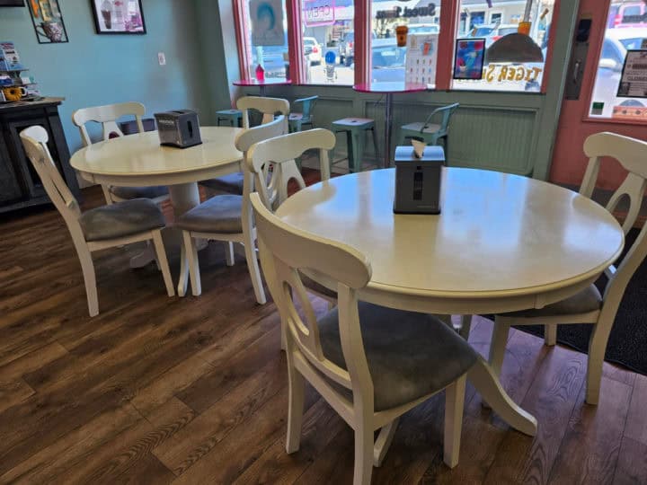 Indoor seating with tables and chairs near the front windows of the bakery