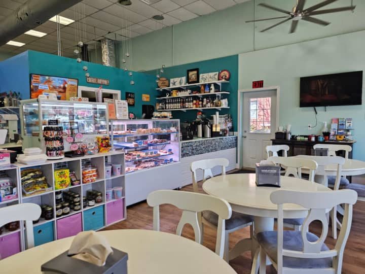 white tables and chairs near the counter with macarons and sweets on display