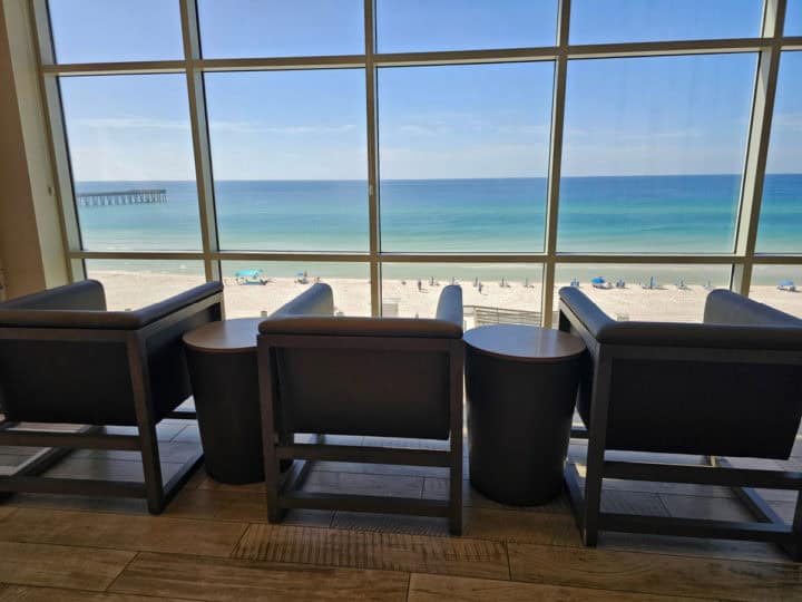 Chairs next to a large window over looking the Gulf of Mexico and white sand beach