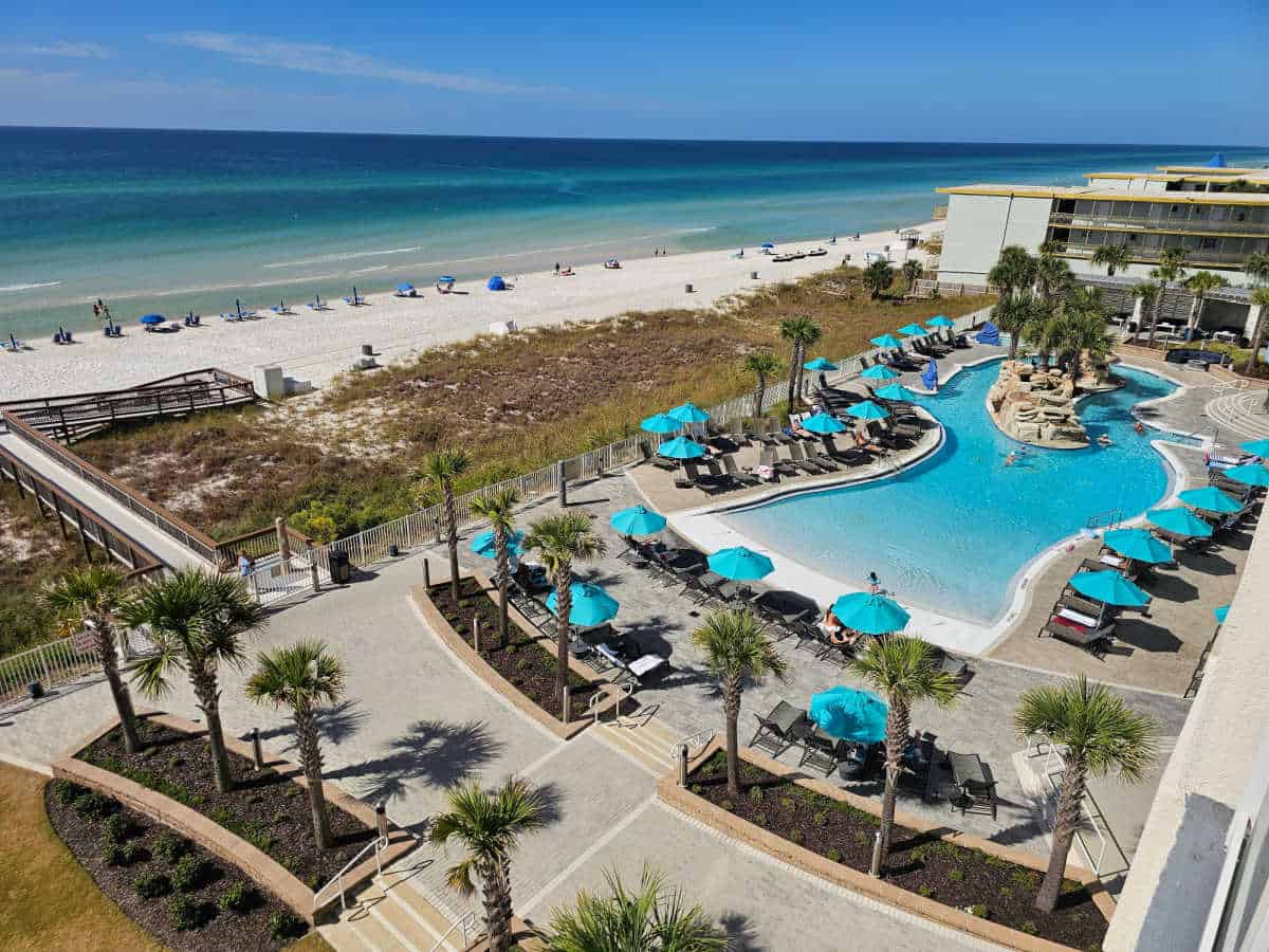 Looking down on a heated pool, pool umbrellas, lazy river, and beach access along the Gulf of Mexico