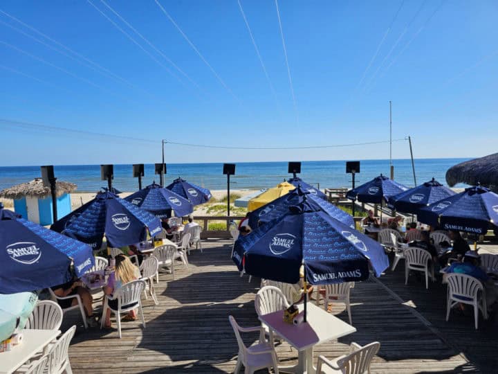 Blue umbrellas over tables leading out to the Gulf