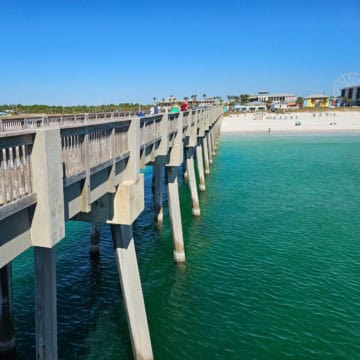 Looking down the Russell Fields Pier to the white sand beach and people on the beach