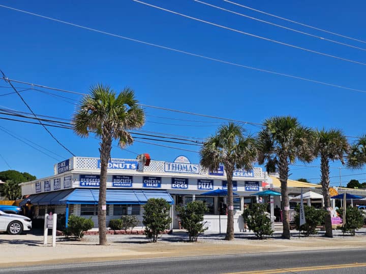 Blue and white Thomas Donuts building with palm trees in front of it