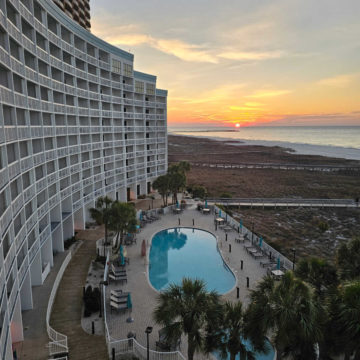 Looking down the side of the Island House Hotel with a pool below and sunrise over the Gulf of Mexico