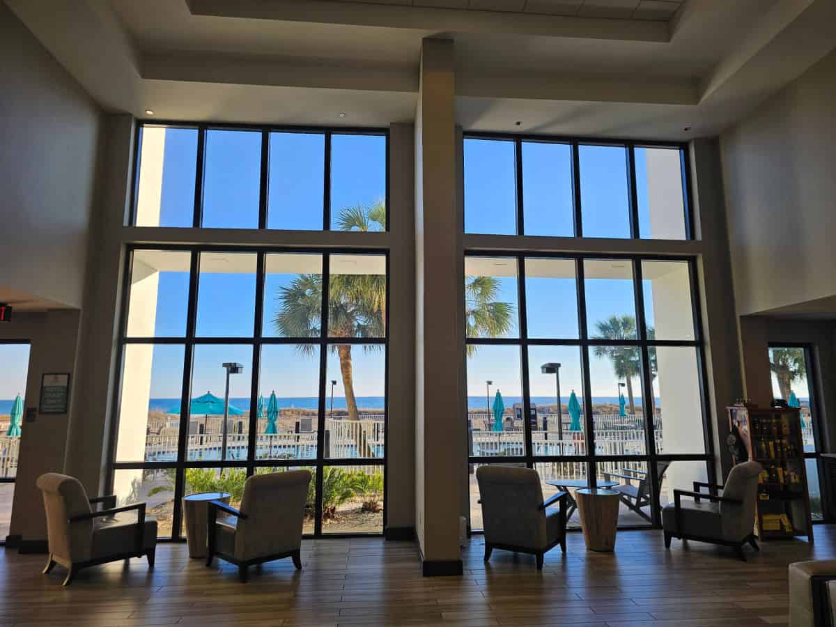 chairs in front of large picture windows looking out over a pool, palm trees, and the Gulf of Mexico