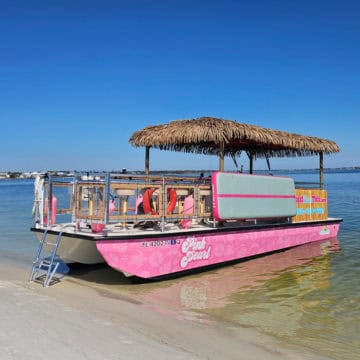 Pink Pearl Tiki Boat docked on the sand