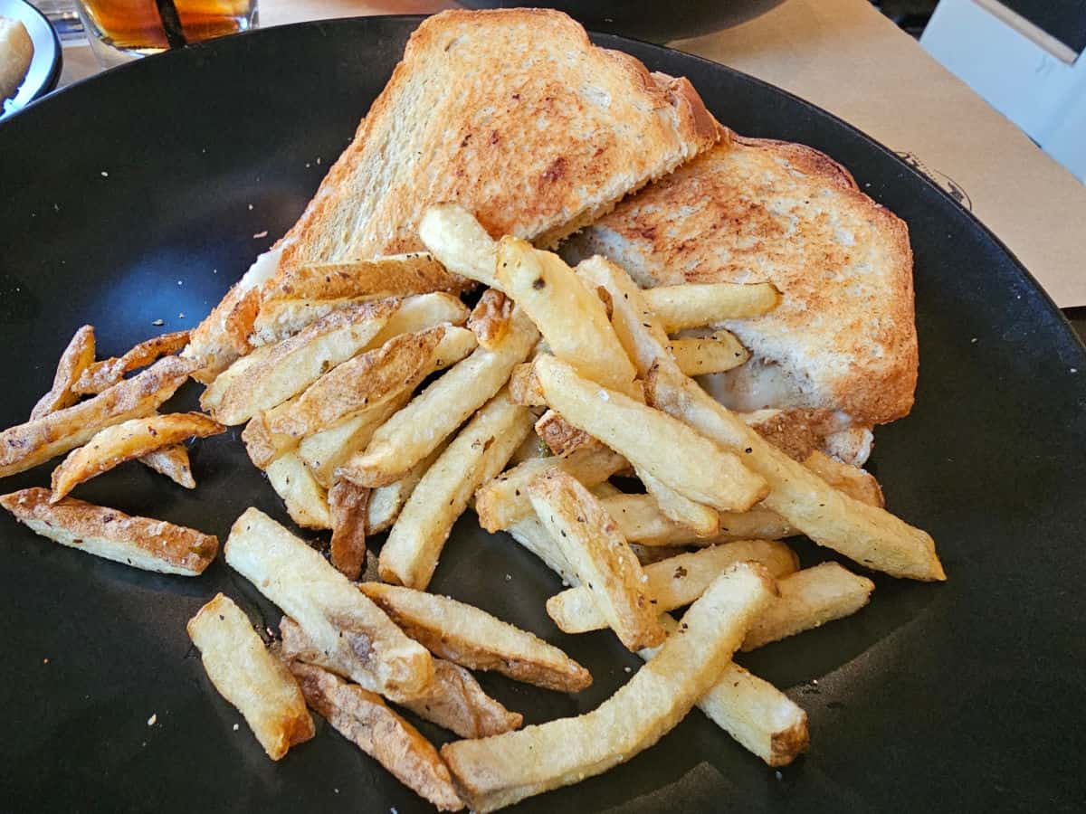 grilled cheese and fries on a black plate