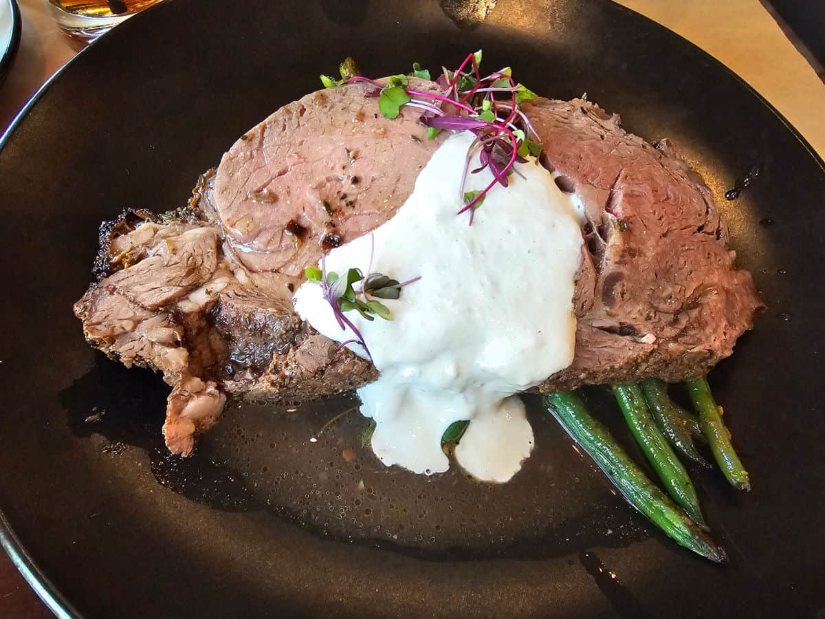 Prime rib with horseradish sauce and asparagus on a black plate