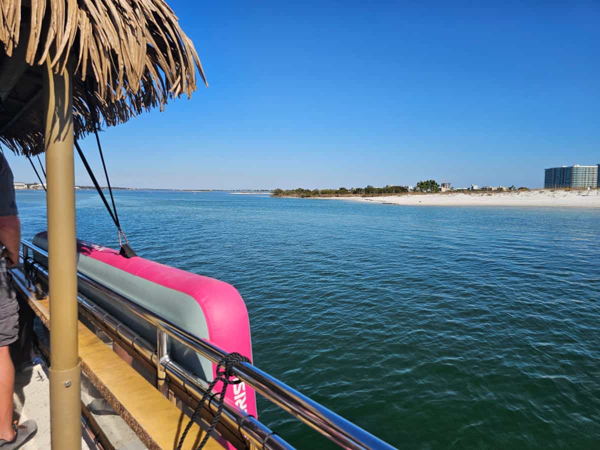 Looking over the side of a tiki boat to the water and Orange Beach islands