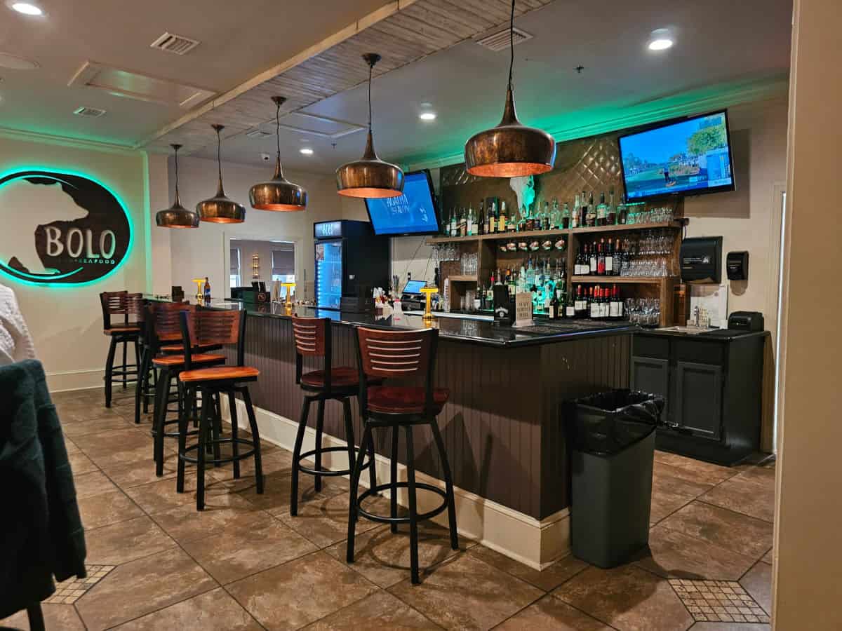 BOLO sign on the wall next to an indoor bar with two tvs, copper lamps over the bar