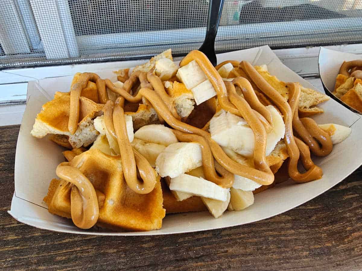 White paper bowl with waffles, banana, and peanut butter
