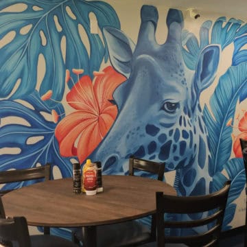 Blue Giraffe mural behind a table and chairs