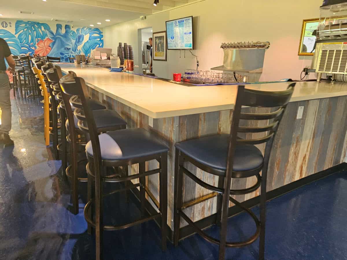 Indoor bar with tall chairs leading down to a Blue Giraffe mural on the wall