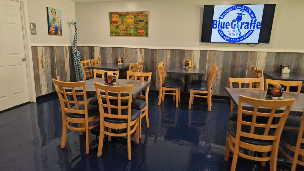 Indoor seating with tables and chairs below a Blue Giraffe sign