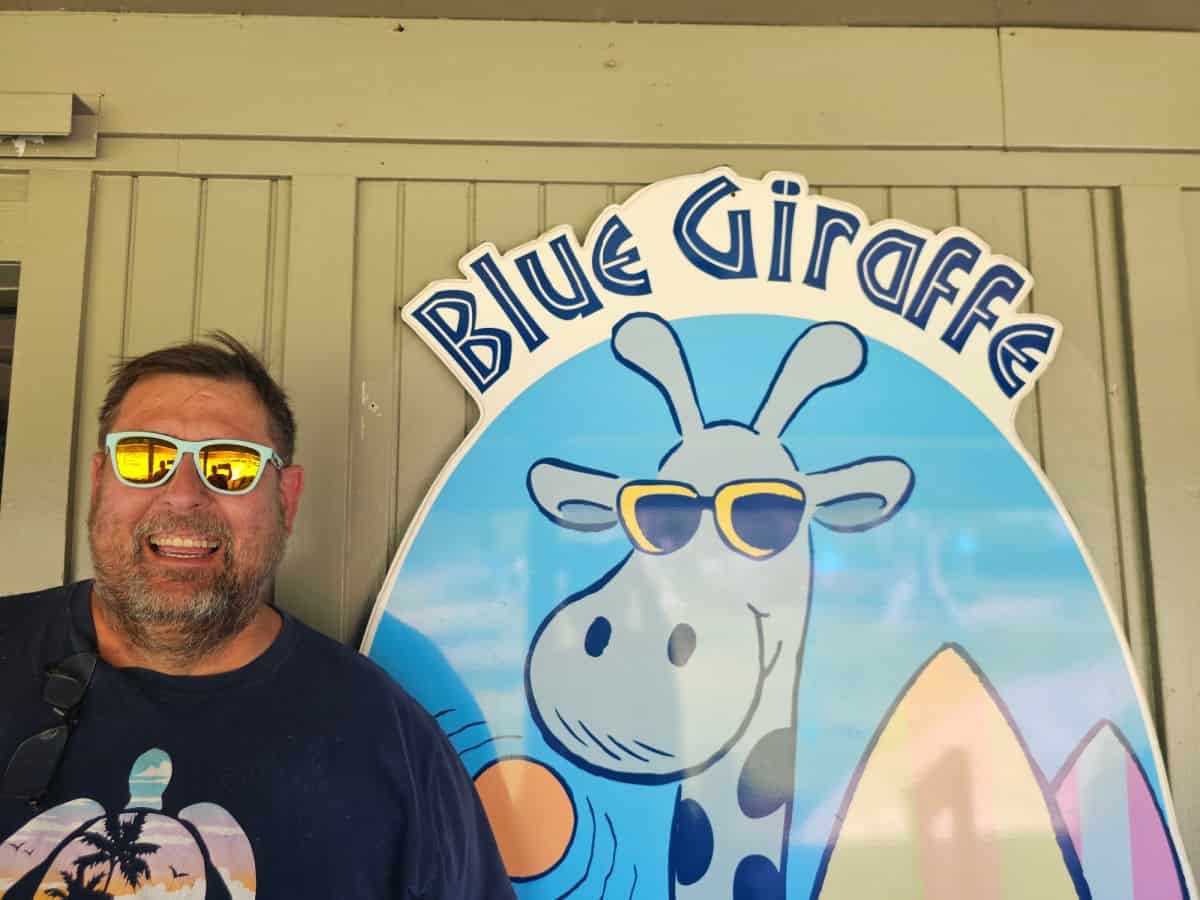 John next to the Blue Giraffe sign