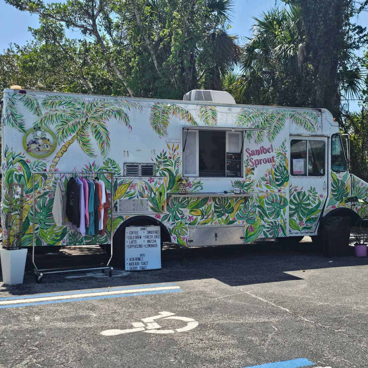 Sanibel Sprout truck with plants painted all over it. Rack of t-shirts and sign