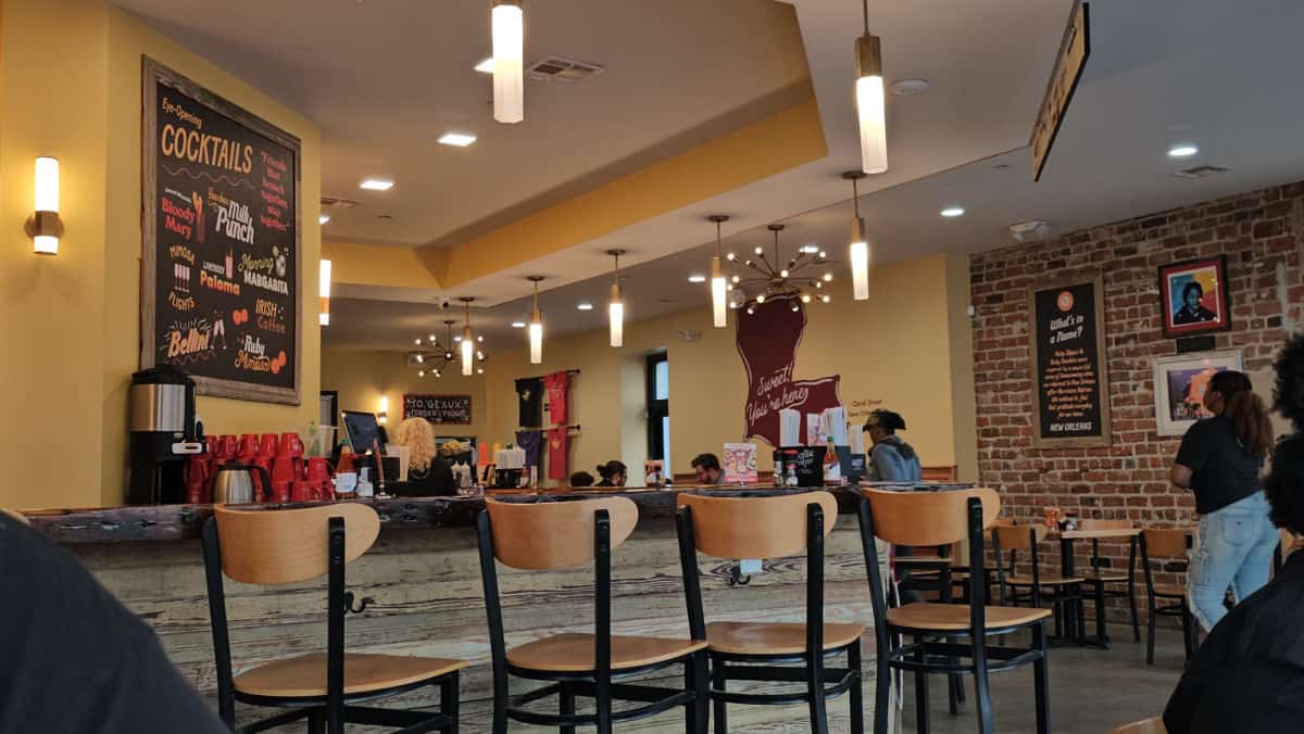 indoor bar with tall chairs, Eye opening cocktails sign on the back wall