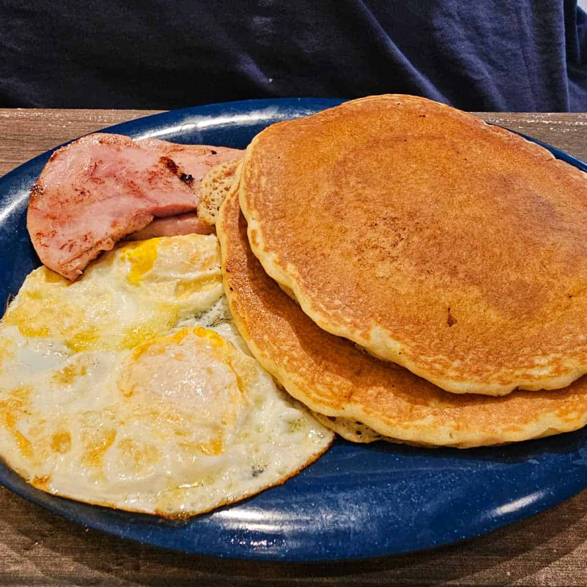 pancakes eggs and ham on a blue plate