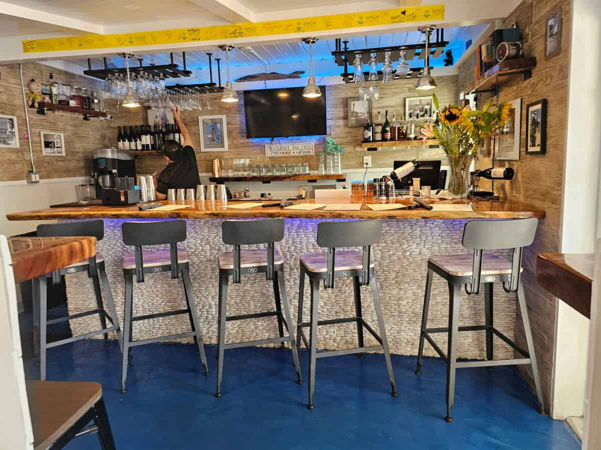 bar seating inside wickies lighthouse restaurant with glasses hanging from a holder