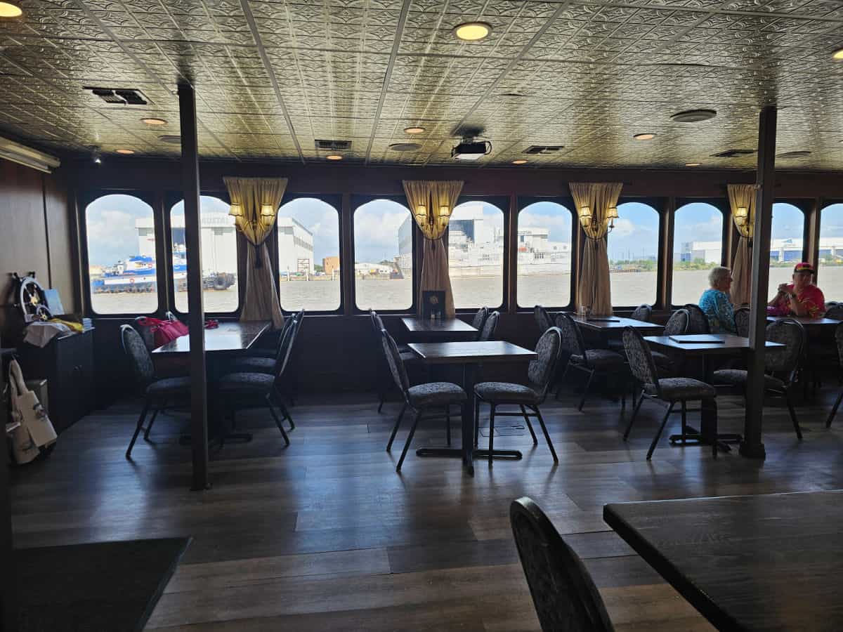 interior of the Perdido Queen boat with tables and chairs set up looking out the window to the river