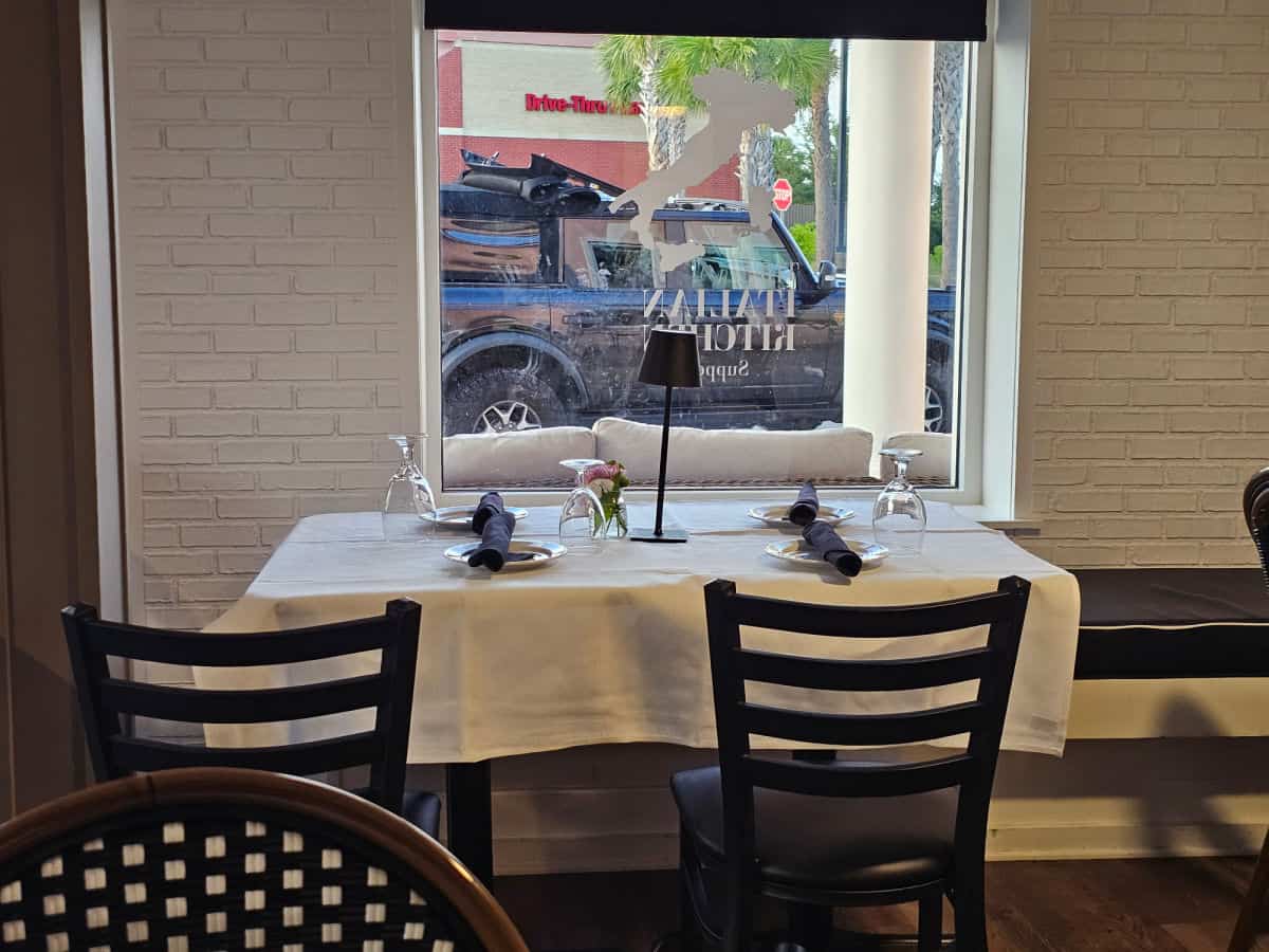 table and chairs next to a window with Italian Kitchen embossed on it