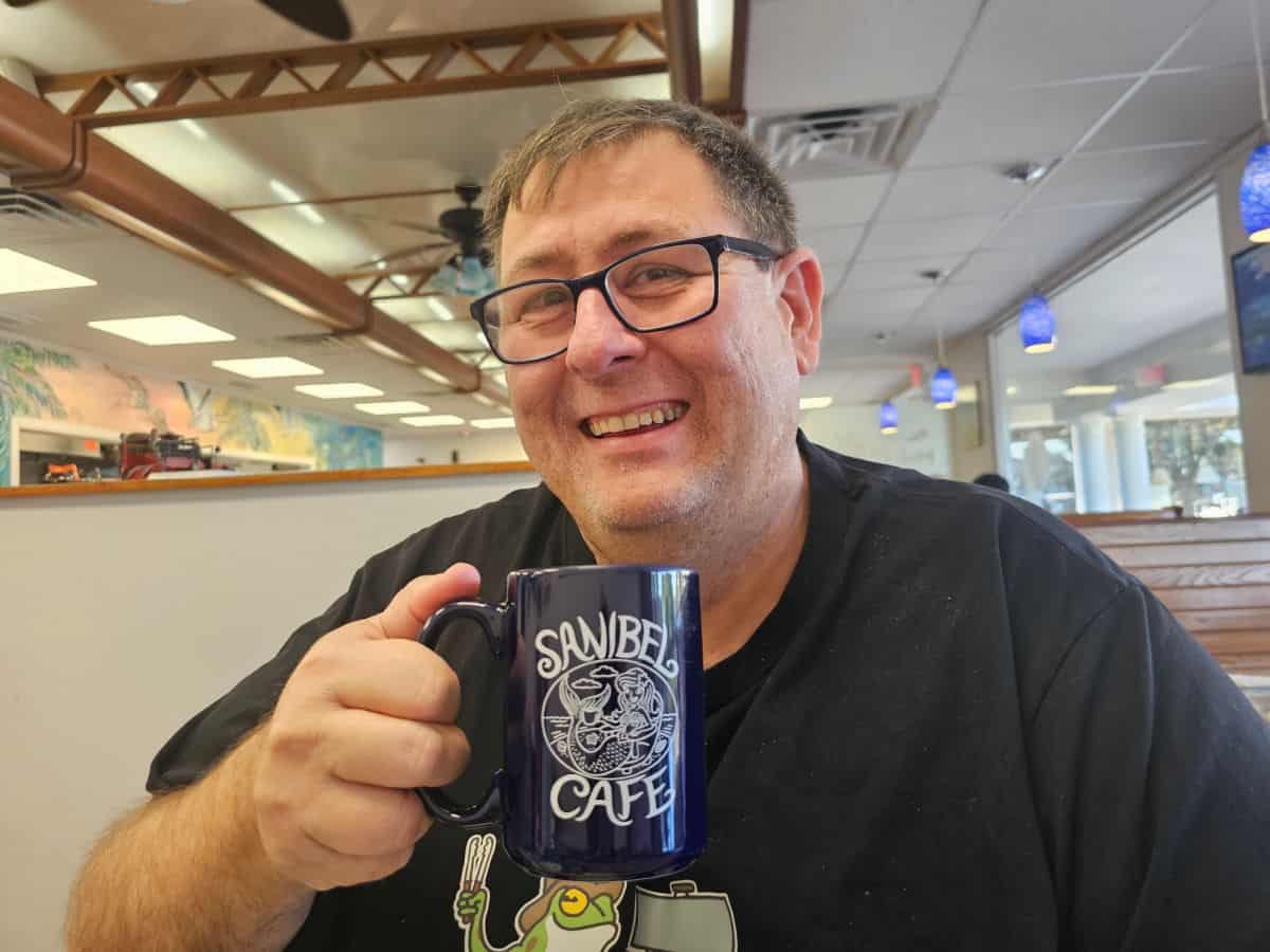 John holding a Sanibel Cafe blue coffee mug
