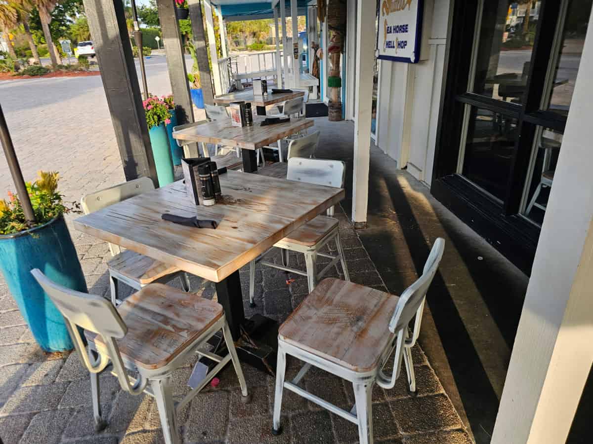 outdoor seating area with tables and chairs, potted plants next to the tables