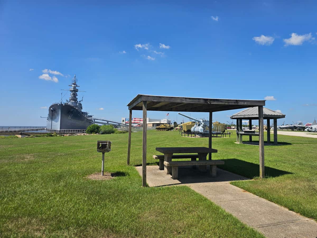 covered picnic table with the uss alabama in the distance