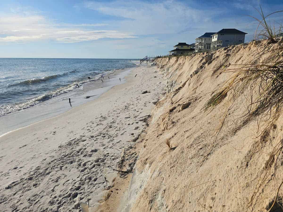 Steep sand cliff with houses over the top with sandy beach to the Gulf of Mexico