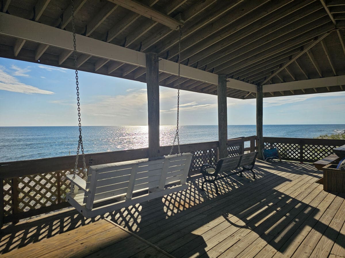 white swing under a pavilion with the Gulf of Mexico in front of it