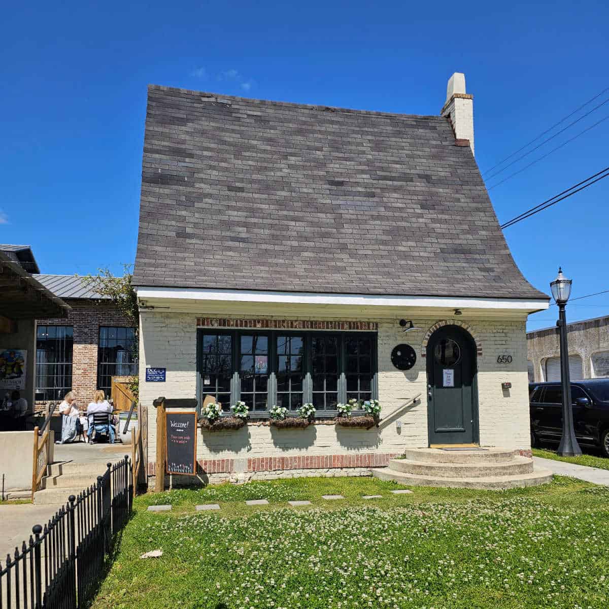 The cheese cottage exterior with steps to the front door and flowers in baskets by the window