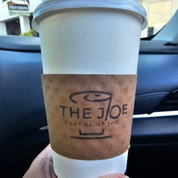 hand holding a coffee cup from The Joe Port Saint Joe