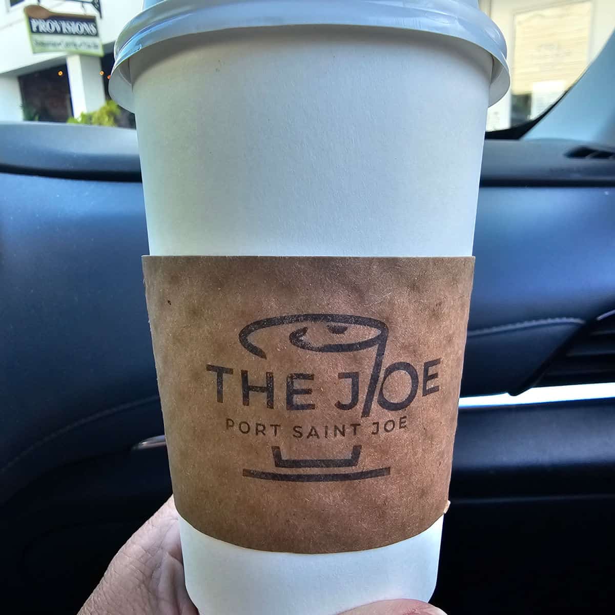 hand holding a coffee cup from The Joe Port Saint Joe