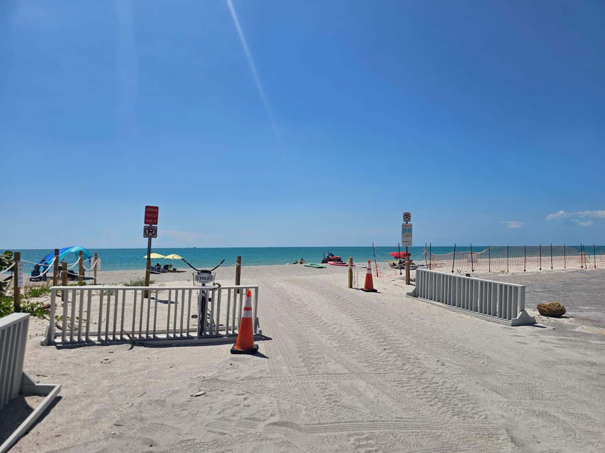 Bike racks leading onto the Andy Rosse Lane Beach with the gulf in the background on a blue sky day