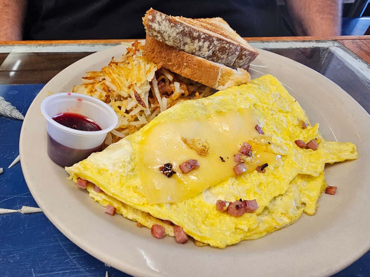 ham and cheese omelet on a white plate with toast and hashbrowns