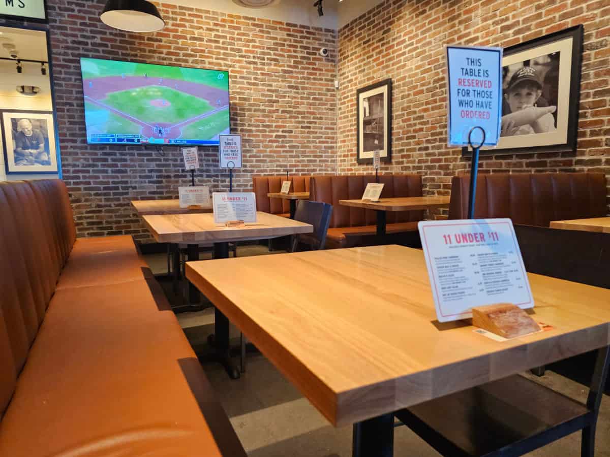 indoor seating with a long bench and tables, booths along the wall, tv on the wall