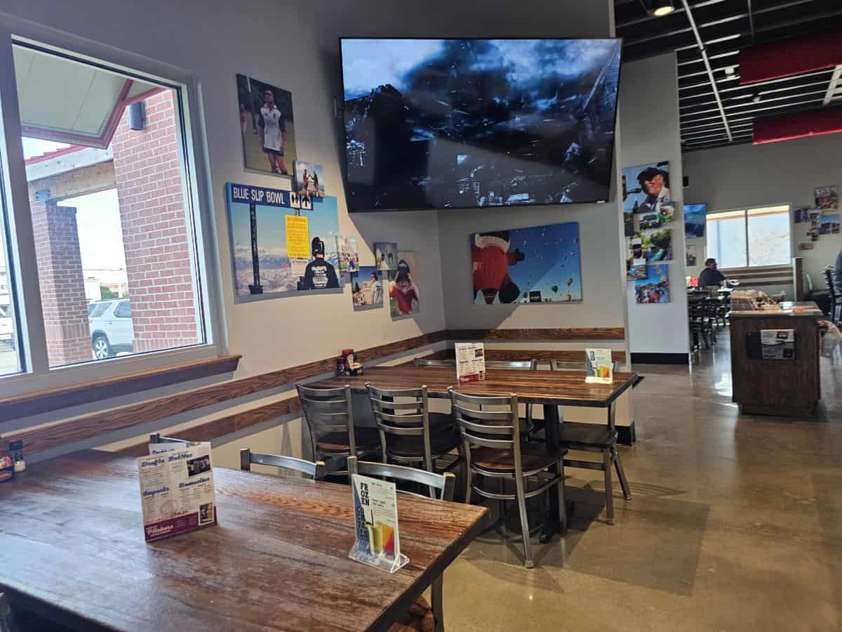 Interior seating in Mugshots with tables and chairs below a giant tv