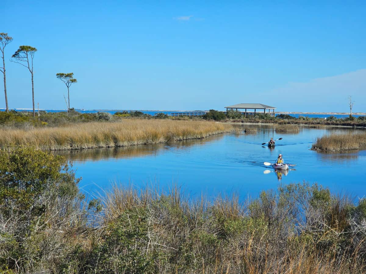 kayaks on the water with a covered pavilion and boardwalk in the background