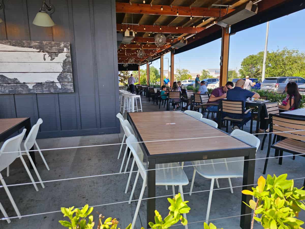 Outdoor seating with tables and chairs under a cover at Jim n Nicks BBQ