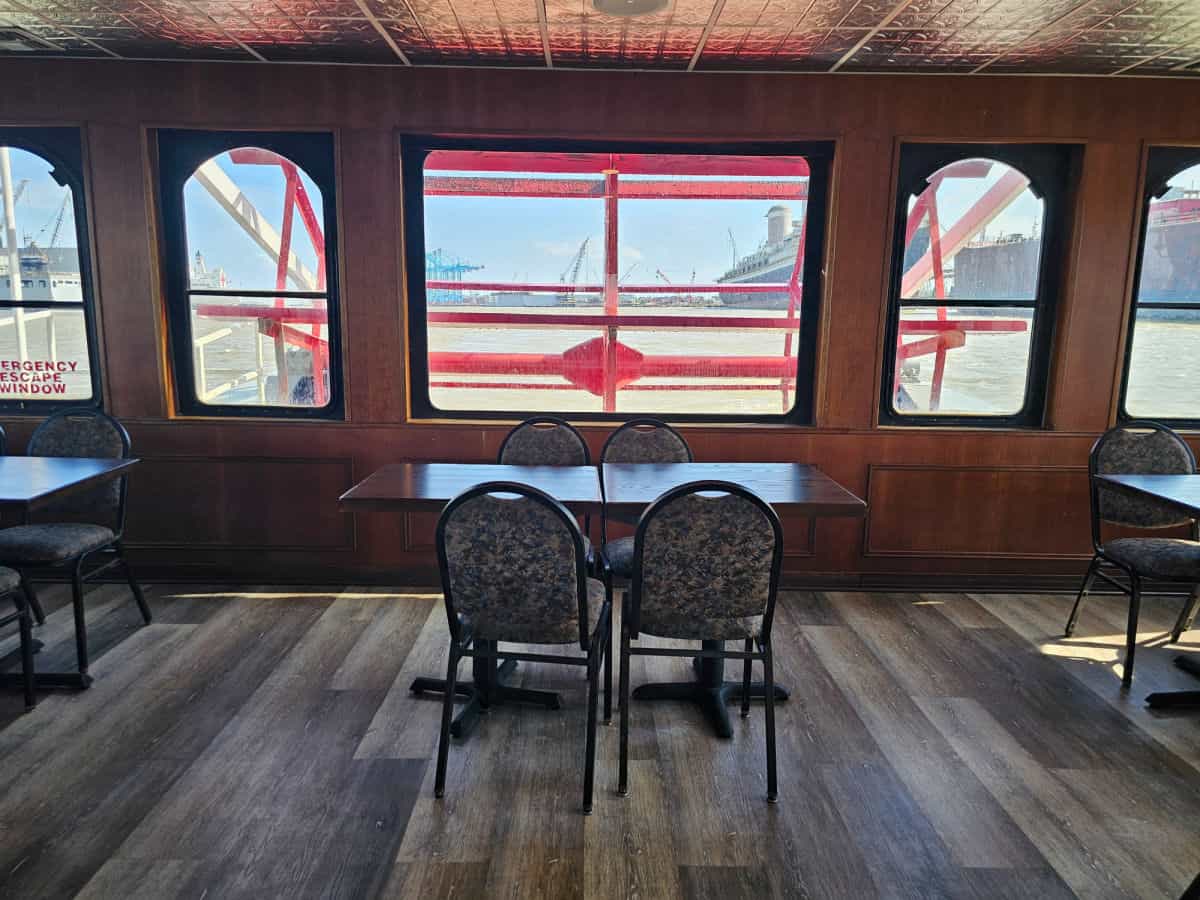inside the Perdido Queen Boat looking out at the paddlewheel over a table and chairs