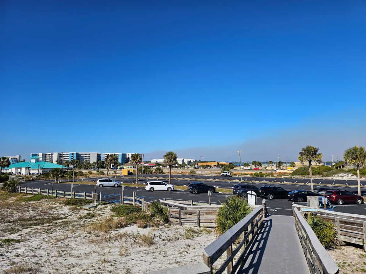 Looking over a boardwalk and parking lot on a blue sky day