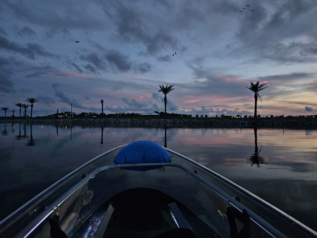 Looking over a clear kayak to pam trees and sunset